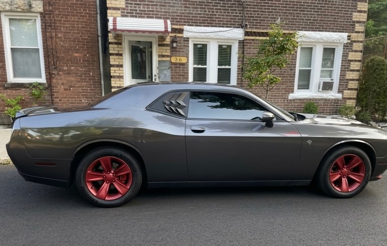 Same Dodge Challenger after exterior detail, paint and red wheels restored to a deep shine