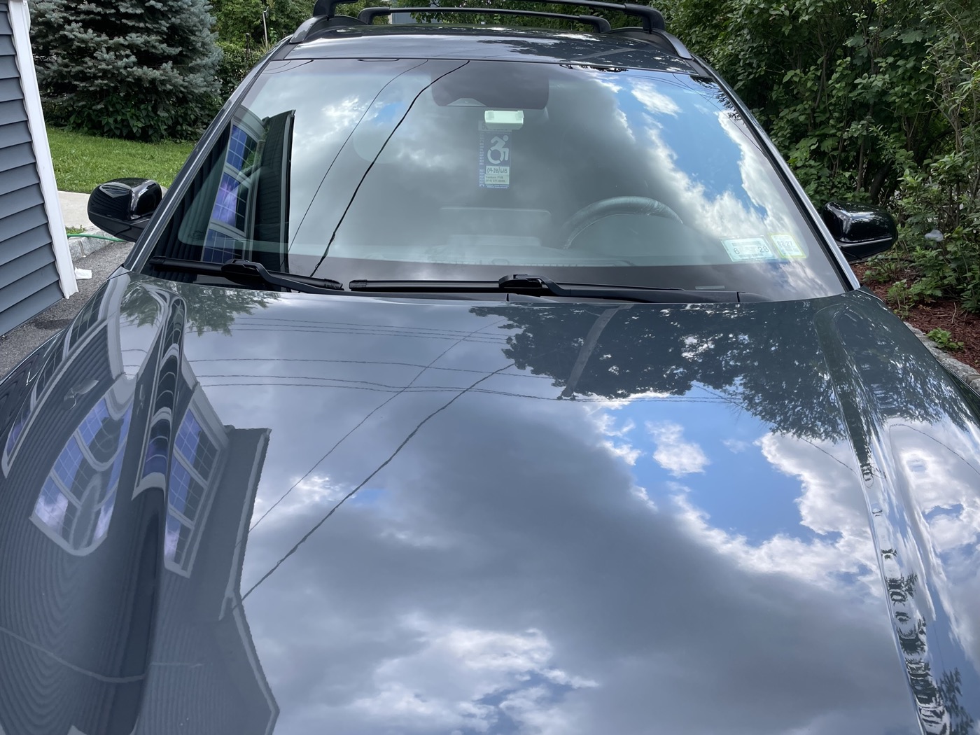 Glossy black SUV hood and windshield after full detail, deep reflective shine